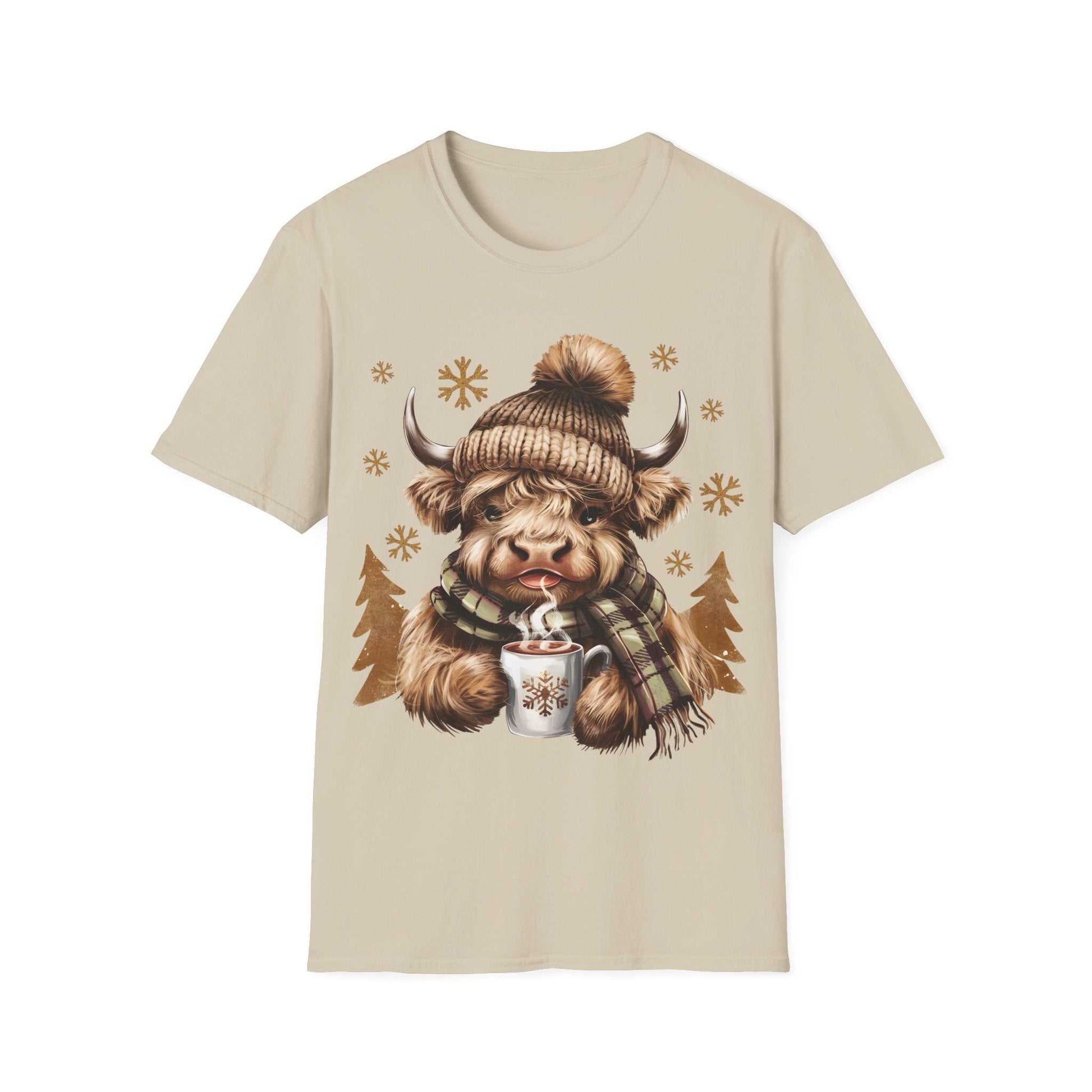 Beige t-shirt featuring a cozy Highland Cow wearing a knit hat and plaid scarf holding a hot chocolate mug with snowflakes.