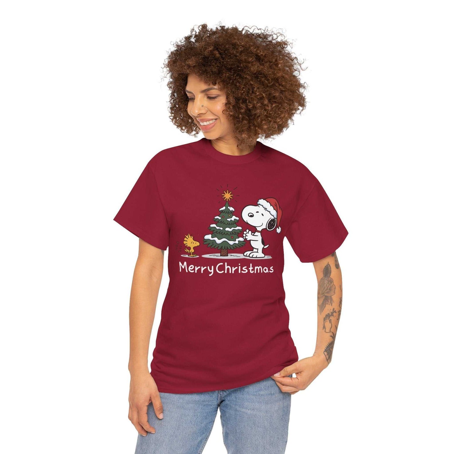 Woman wearing red Snoopy & Woodstock Merry Christmas holiday T-shirt with Snoopy in Santa hat next to Christmas tree and Woodstock character