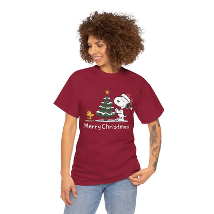 Woman wearing red Snoopy & Woodstock Merry Christmas holiday T-shirt with Snoopy in Santa hat next to Christmas tree and Woodstock character