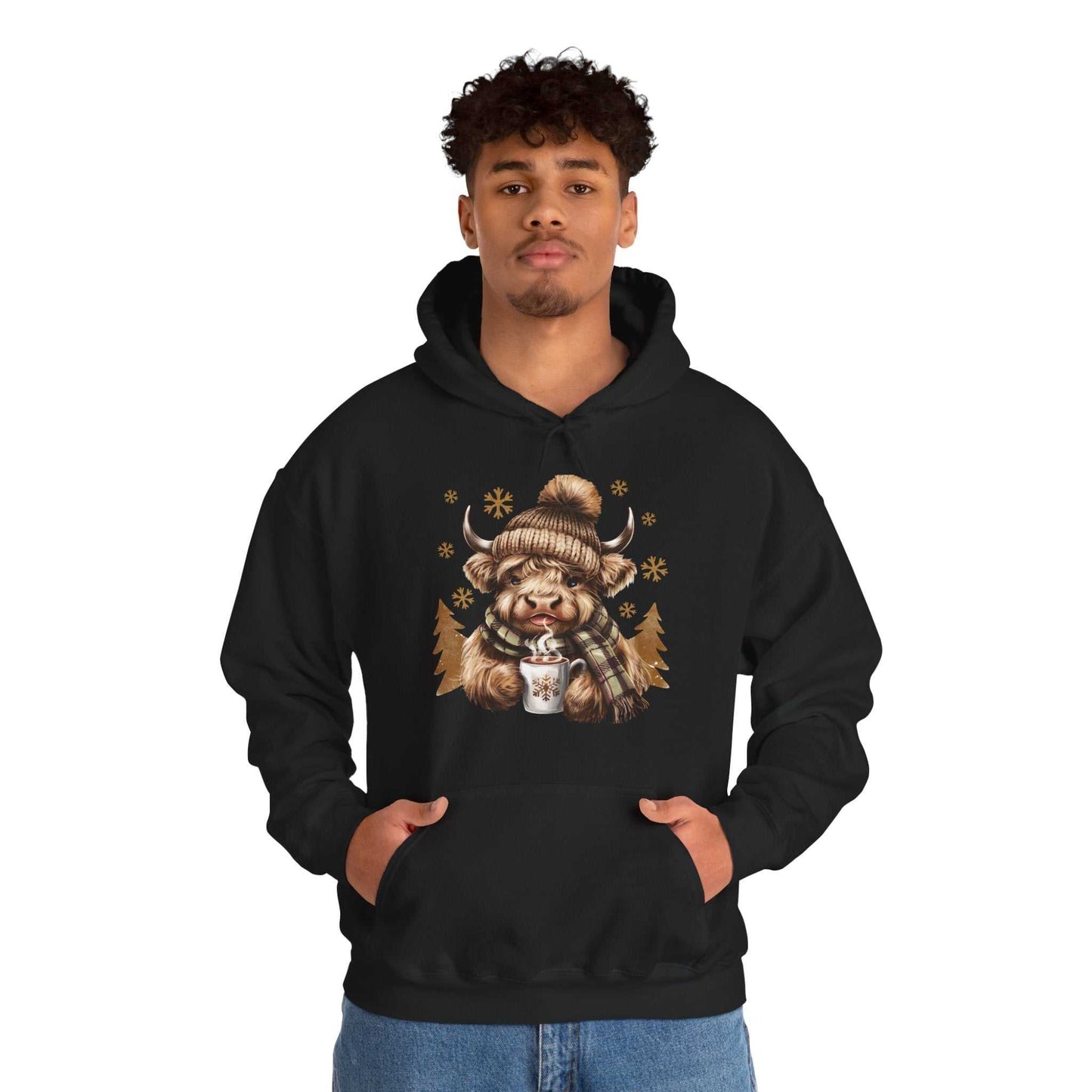 Black hoodie featuring a watercolor Highland Cow wearing a knit hat and scarf holding a mug of hot chocolate with snowflakes, cozy winter design.