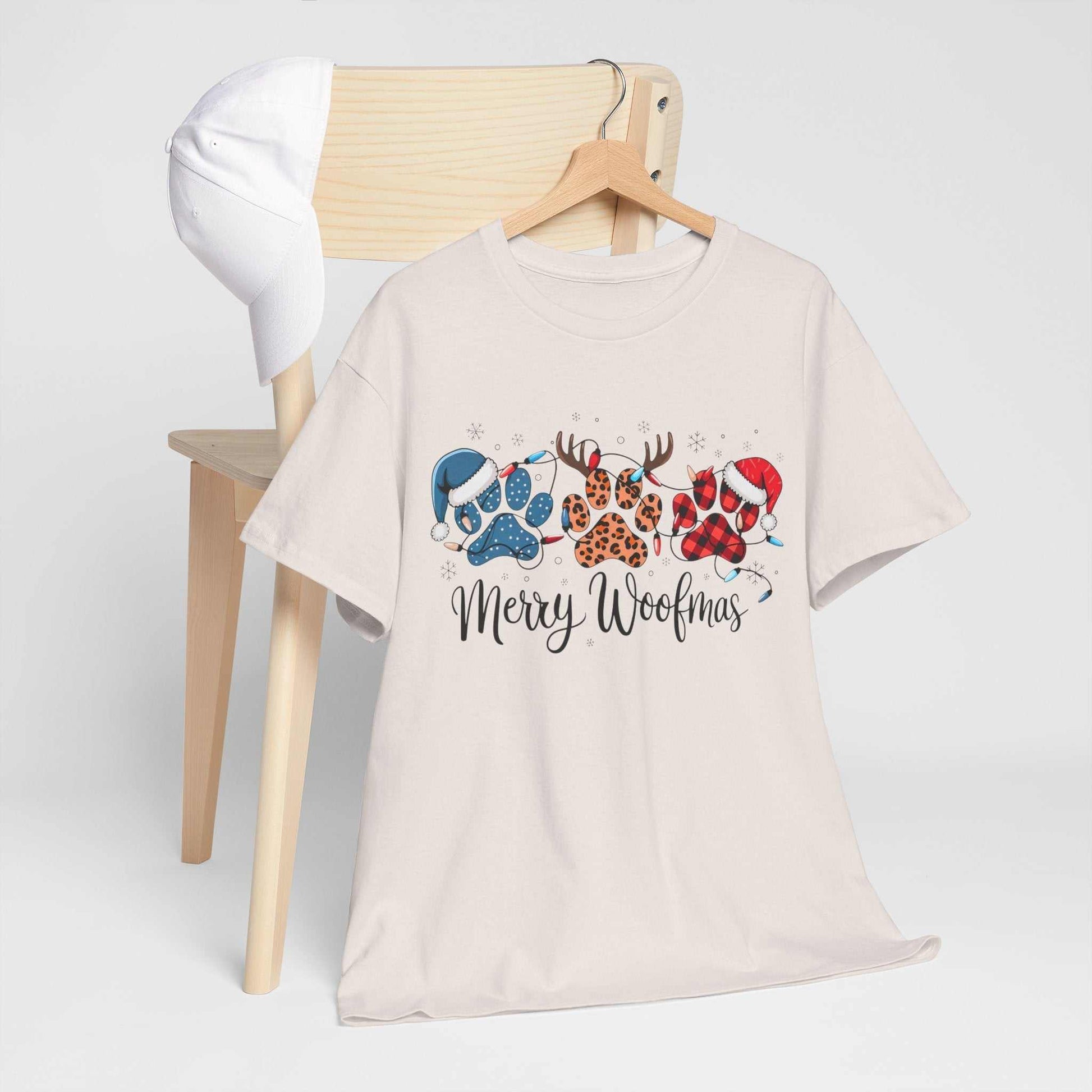 Merry Woofmas Christmas tee with festive paw prints in buffalo plaid, leopard spots, and holiday hats on unisex heavyweight cotton shirt