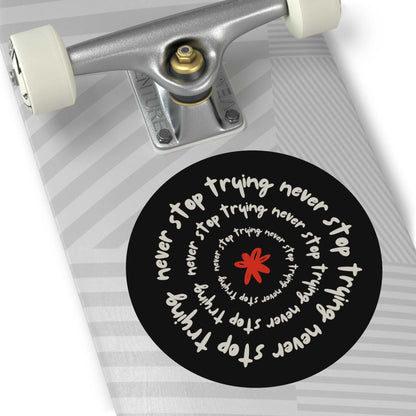 Don't Stop Trying motivational round vinyl sticker on skateboard with spiral white text and red flower design