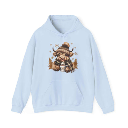 Light blue Highland Cow Hoodie with a cozy watercolor illustration of a Highland cow wearing a knit hat and plaid scarf holding a steaming mug with snowflakes.