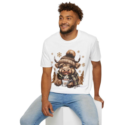 Man wearing white Highland Cow and hot chocolate winter-themed graphic T-shirt sitting on white cube