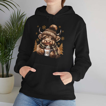 Black Highland Cow hoodie with cozy winter design of cow in knit hat and scarf holding hot chocolate mug