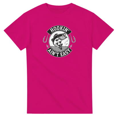 Hookin' Ain't Easy T-Shirt in pink with fishing graphic and humorous slogan for fishing enthusiasts