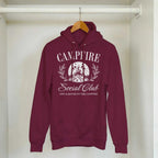 Burgundy Campfire Social Club cozy hoodie with front pouch, double-lined hood, and printed campfire design.