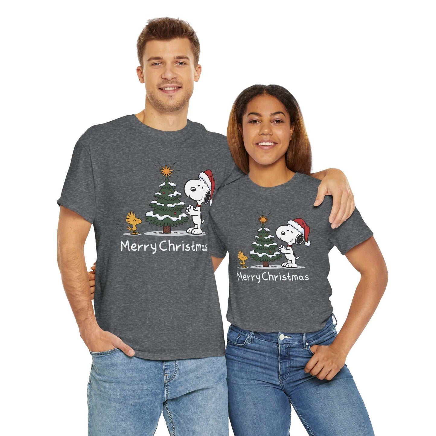 Couple wearing gray Snoopy & Woodstock Merry Christmas holiday graphic t-shirts with Snoopy in a Santa hat next to a Christmas tree.