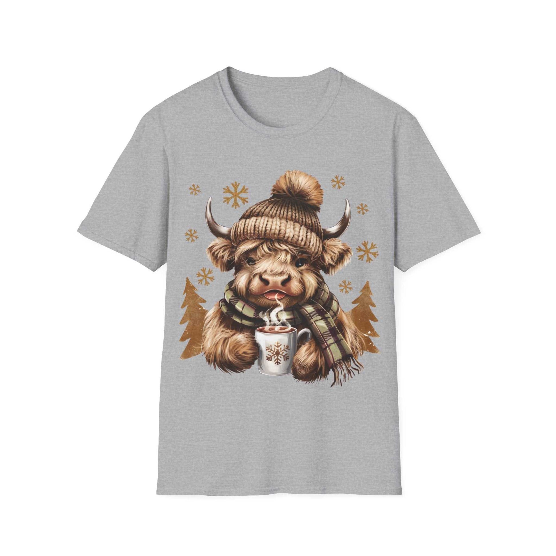 Gray t-shirt with a cozy Highland Cow wearing a knit hat and scarf holding a hot chocolate cup surrounded by snowflakes and pine trees