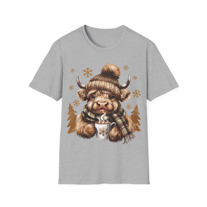 Gray t-shirt with a cozy Highland Cow wearing a knit hat and scarf holding a hot chocolate cup surrounded by snowflakes and pine trees