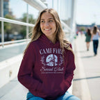 Woman wearing a maroon Campfire Social Club Cozy Hoodie with front pouch pocket outdoors