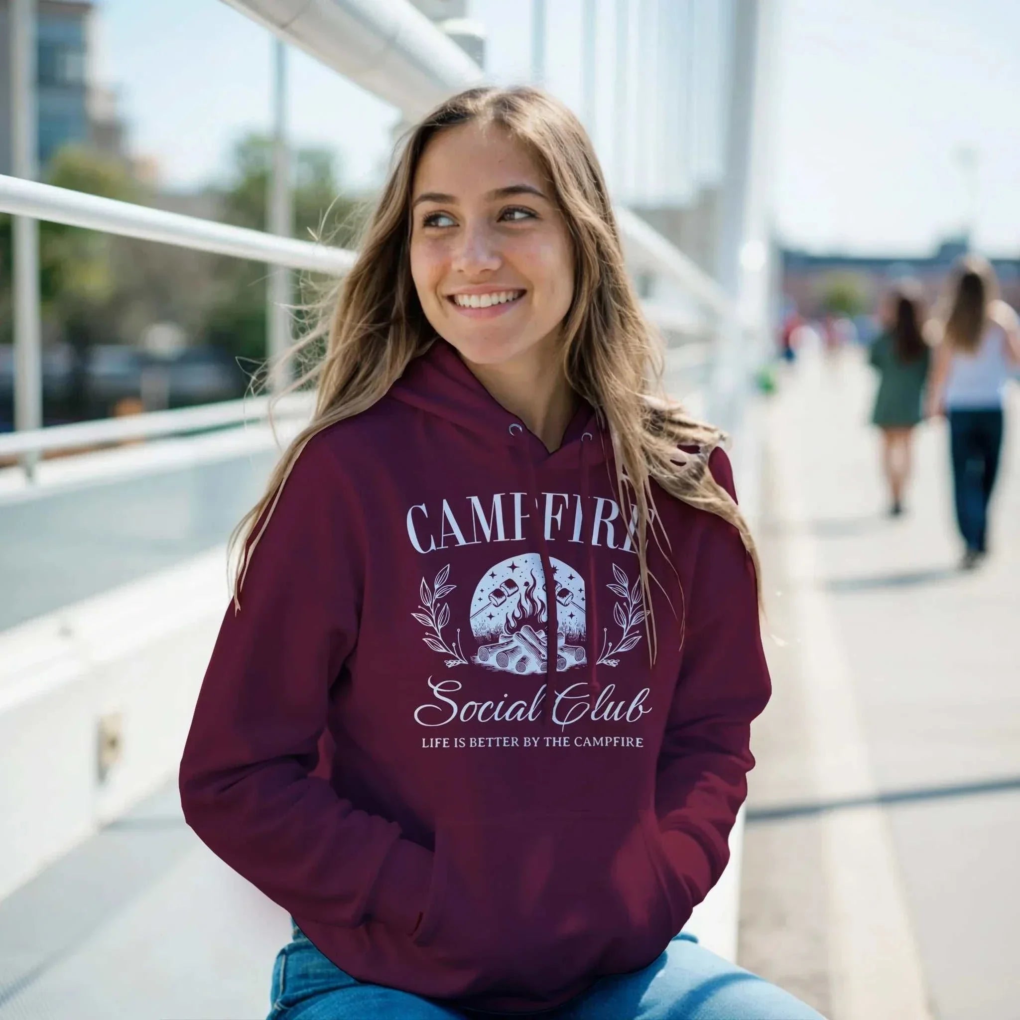 Woman wearing a maroon Campfire Social Club Cozy Hoodie with front pouch pocket outdoors