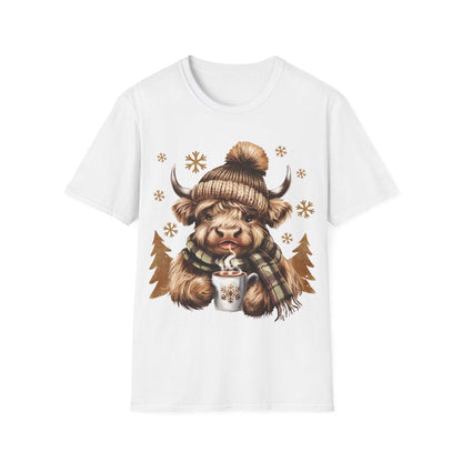White t-shirt featuring a cozy Highland Cow wearing a knit hat and plaid scarf holding a steaming hot chocolate mug with snowflake design.