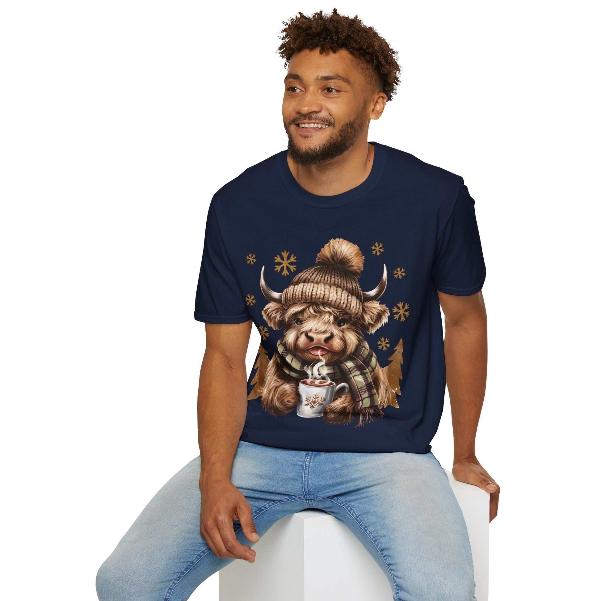 Man wearing navy Highland Cow T-Shirt with cozy winter cow holding hot chocolate design