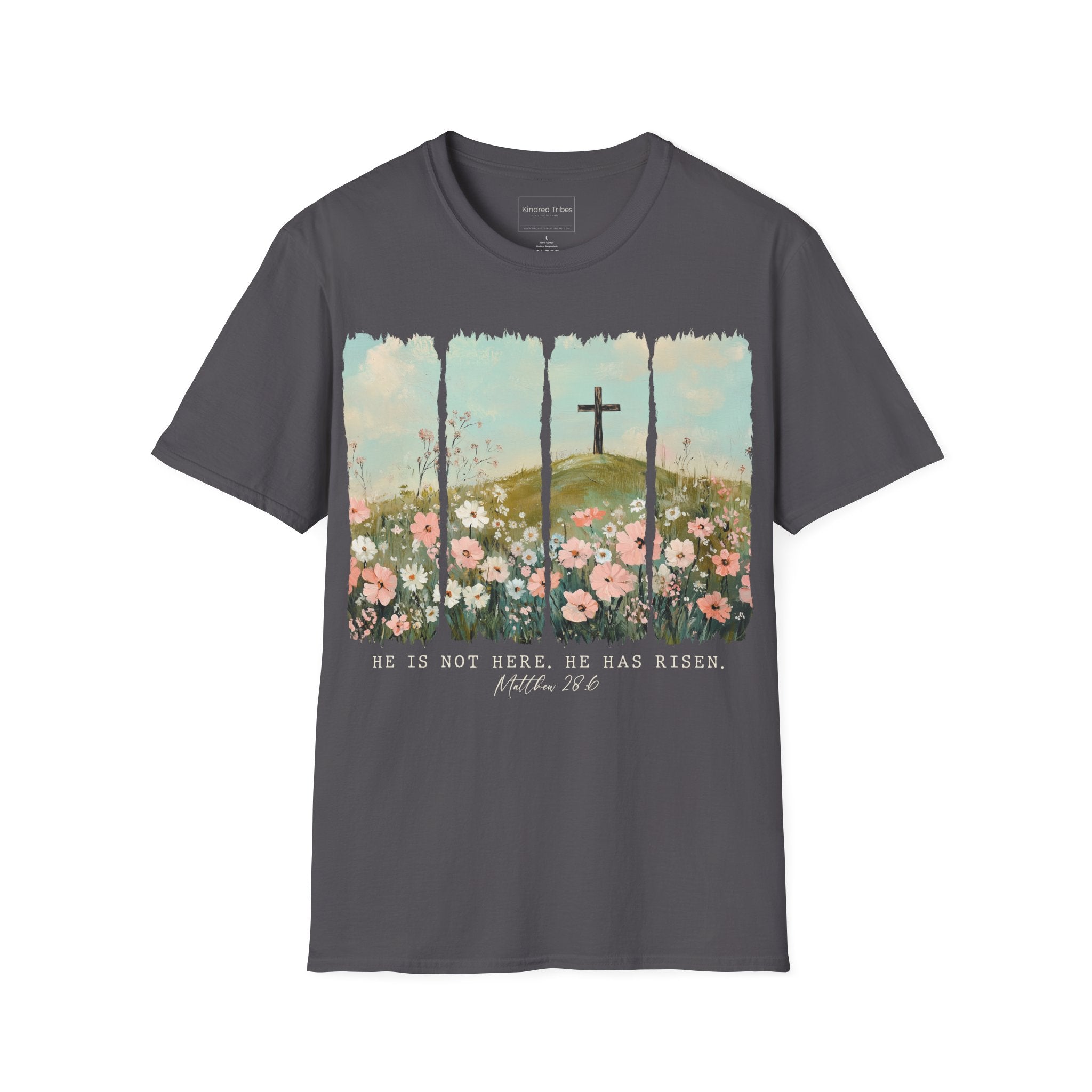 Charcoal Grey Easter He Has Risen - Floral Cross Christian Tee featuring a painterly, four-panel graphic of a serene spring landscape. A wooden cross stands on a green hilltop overlooking a field of pink, white, and red wildflowers under a soft blue sky. Below the artwork, the text reads 'HE IS NOT HERE. HE HAS RISEN.' followed by the scripture 'Matthew 28:6' in elegant cursive.