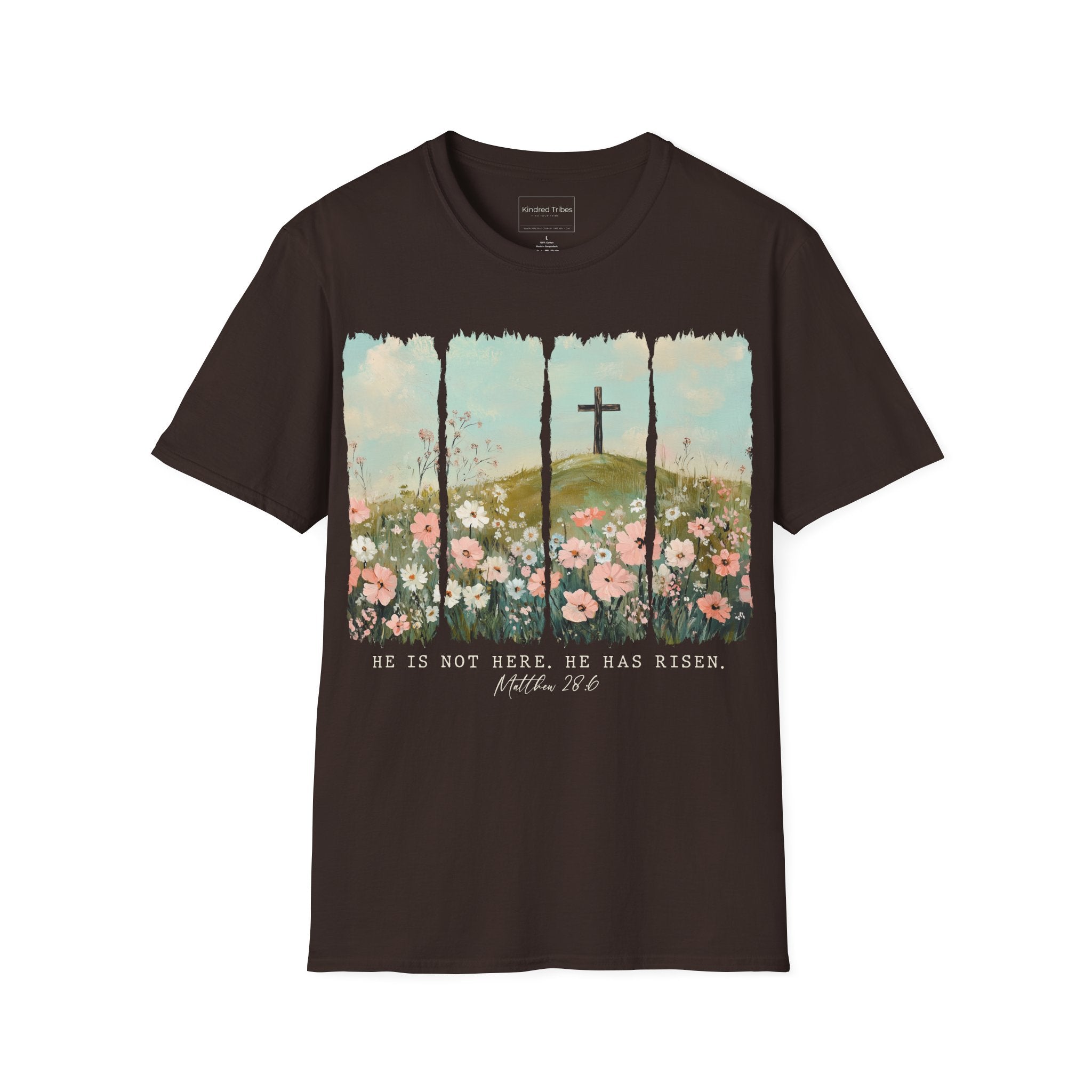 Chocolate Brown Easter He Has Risen - Floral Cross Christian Tee featuring a painterly, four-panel graphic of a serene spring landscape. A wooden cross stands on a green hilltop overlooking a field of pink, white, and red wildflowers under a soft blue sky. Below the artwork, the text reads 'HE IS NOT HERE. HE HAS RISEN.' followed by the scripture 'Matthew 28:6' in elegant cursive.