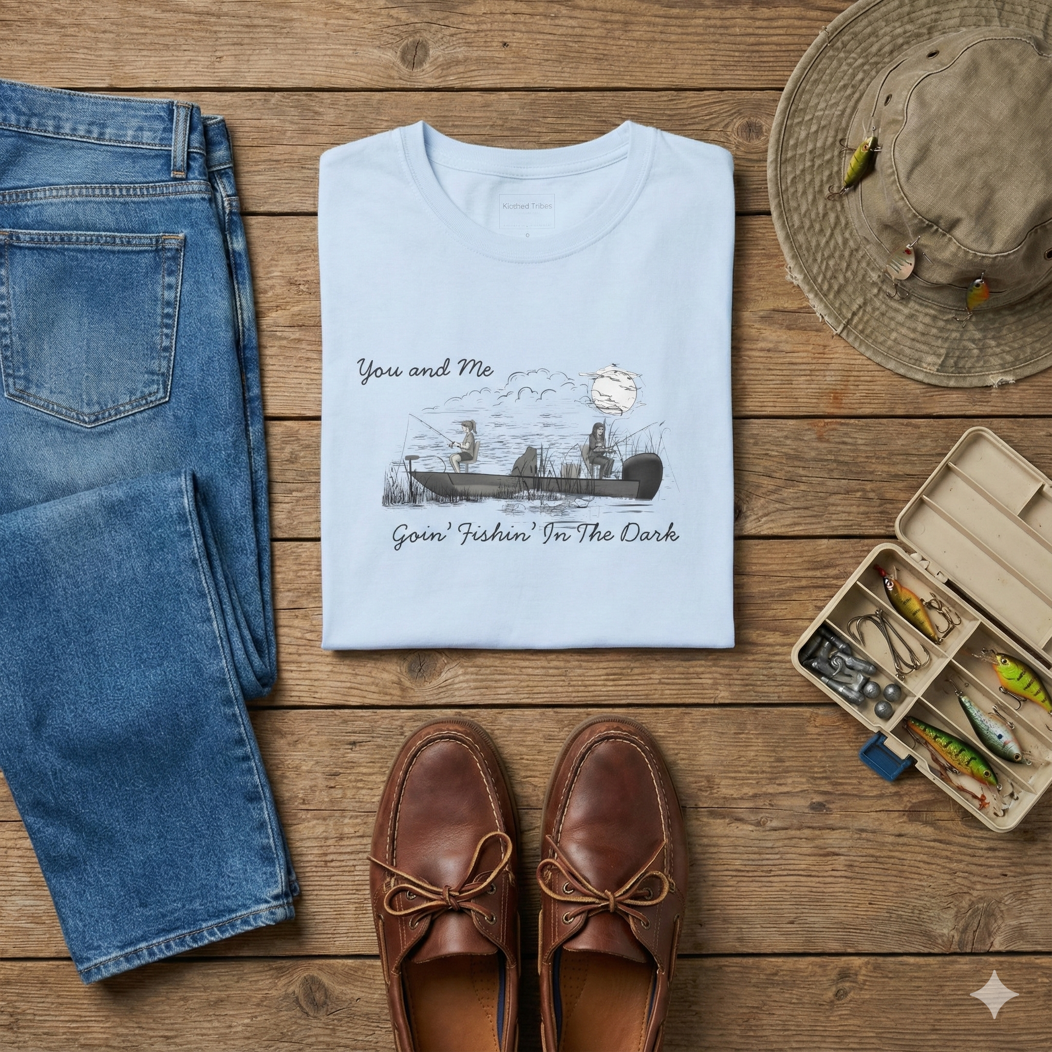 The Best Friends Fishin' In The Dark T-Shirt shows two women in a fishing boat fishing with the moon shining down in a black and white hand sketched print design on a light blue cotton tee.