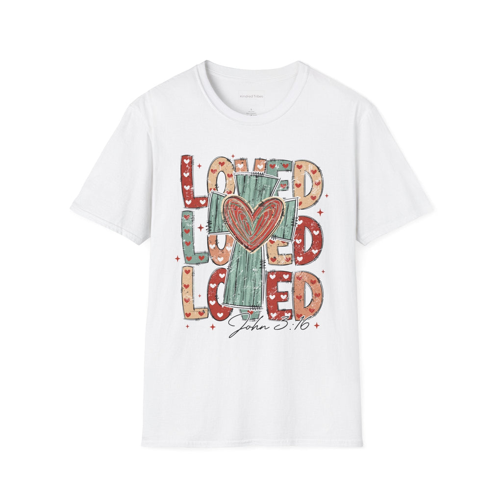 White Loved Cross Heart T-Shirt featuring a large, colorful graphic on the front. The design consists of the word "LOVED" repeated three times in a stacked, chunky block font. The letters are filled with various patterns, including solid colors, stripes, and small hearts in shades of red, sage green, and tan. In the center of the text is a distressed, teal-colored cross with a large, hand-drawn red heart layered over the middle. Below the main graphic, the scripture reference "John 3:16" is written.
