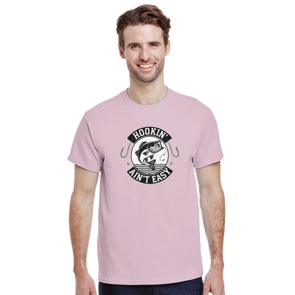 Man wearing a pink Hookin' Ain't Easy T-Shirt with fishing graphic and text on front